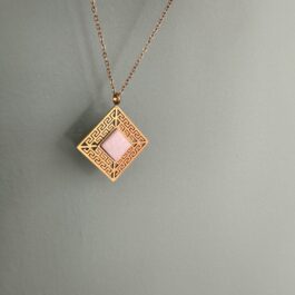 A gold Meandros with white centered marble on a gold stainless steel chain