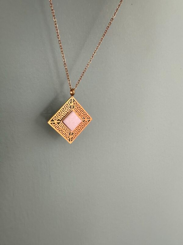 A gold Meandros with white centered marble on a gold stainless steel chain